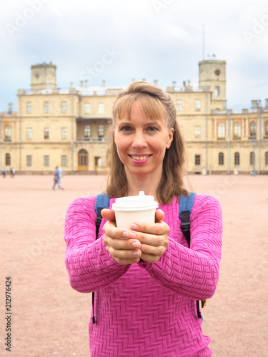 Smiling woman with coffee in a paper cup on the background of architectural attractions. photo