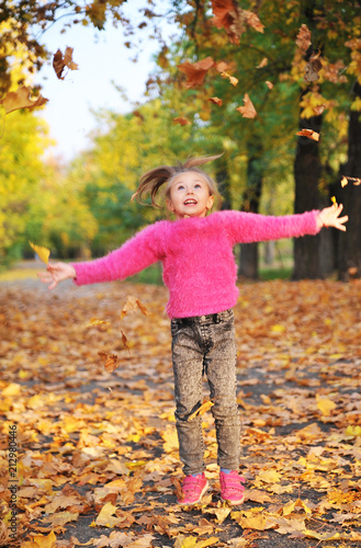 Cute little girl plays with an autumn leaves.