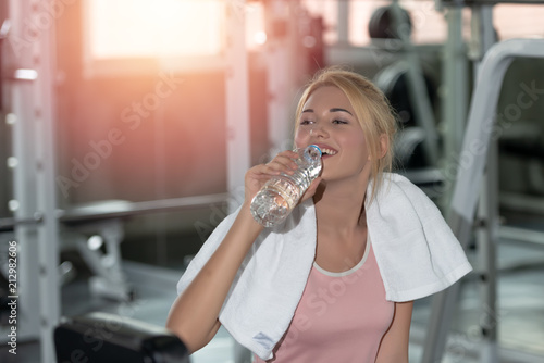 Caucasian young women drinking water after work out exercising in gym. Living healthy lifestyle concept.