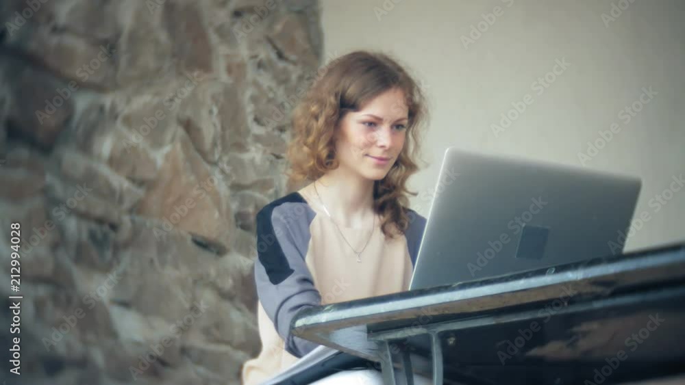 Young beautiful business woman sitting on sofa at table with tablet and looking through paper Young beautiful business woman sitting on sofa at table with tablet and looking through paper