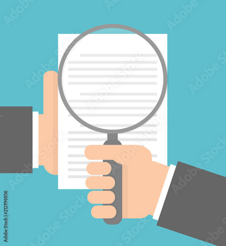 Hand holding magnifying glass over a document