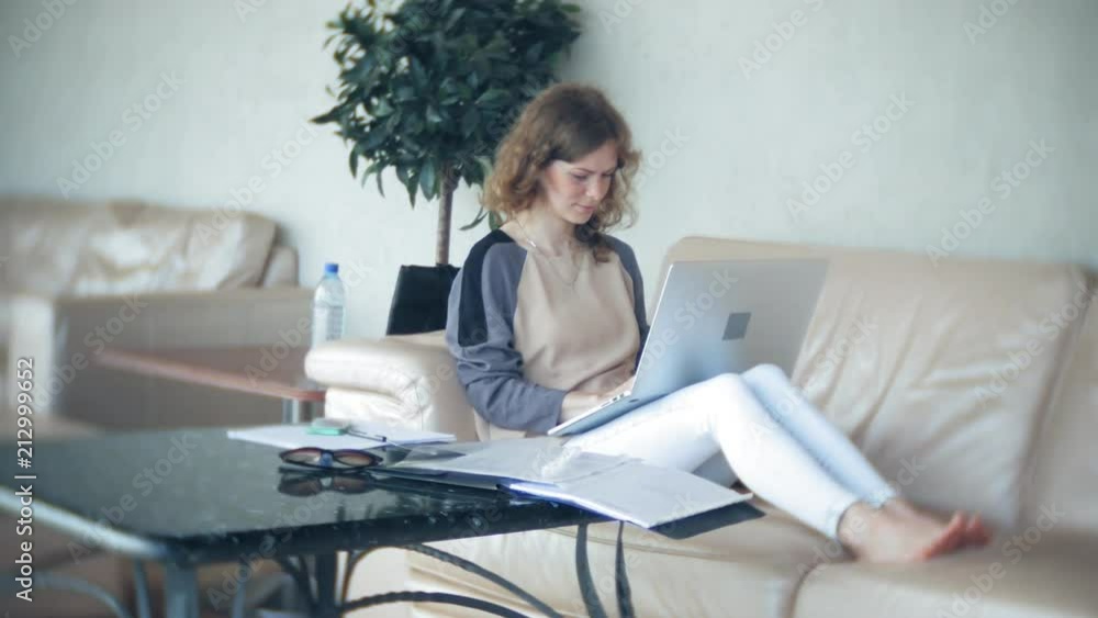 Young beautiful business woman sitting on sofa at table with tablet Young beautiful business woman sitting on sofa at table with tablet