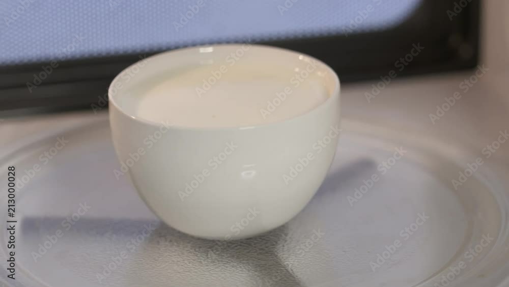 Cup of milk rotating inside microwave. Warming up food inside microwave oven. Cup of milk rotating inside microwave. Warming up food inside microwave oven.