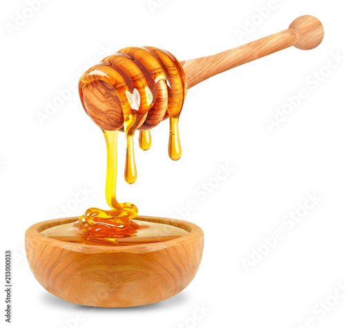 honey dripping into a wooden bowl on a white background