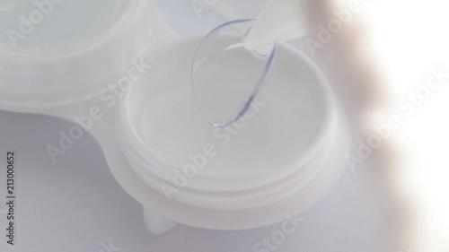 
Tweezer taking contact lens out from storage case.