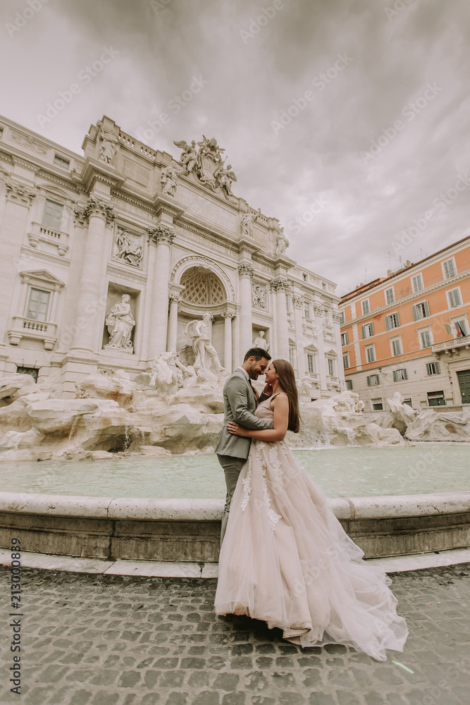 Bride and groom posing in front of Trevi Fountain (Fontana di Trevi), Rome, Italy