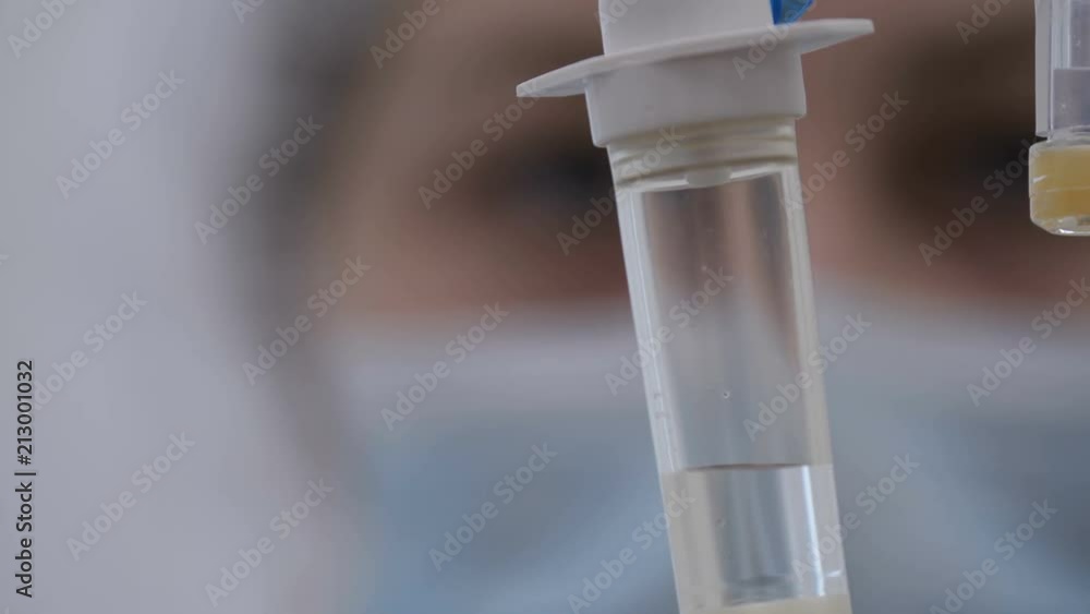 Close-up of drip and face of a nurse in blur Close-up of drip and face of a nurse in blur
