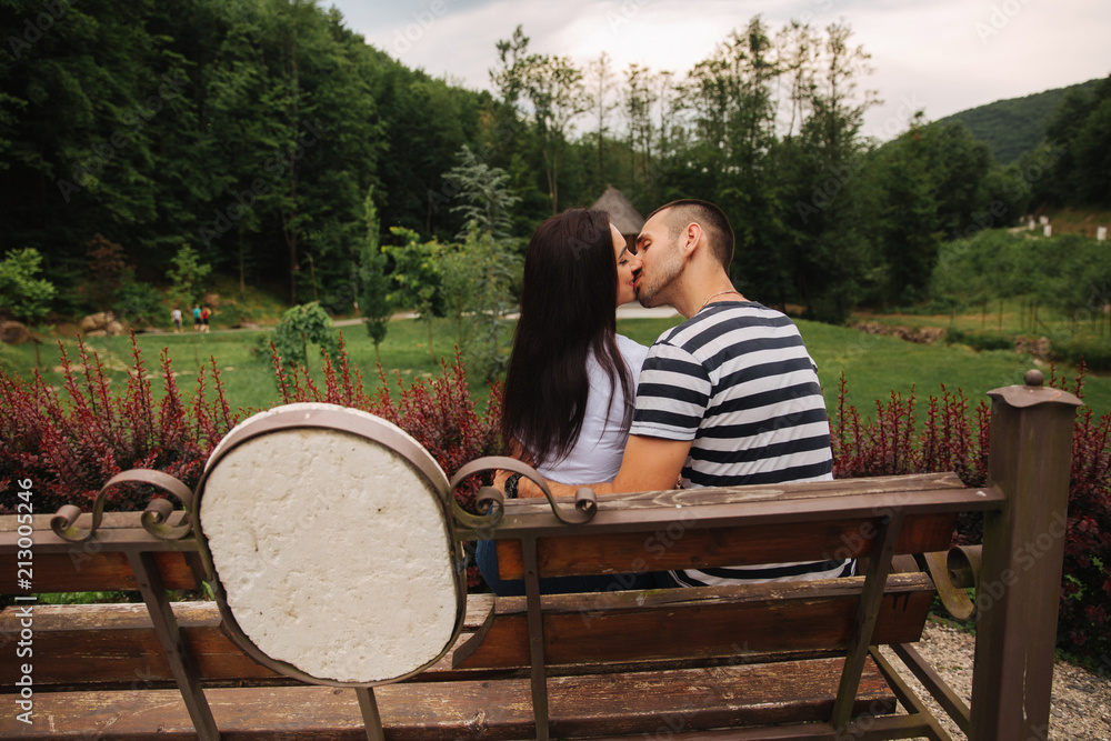 Fototapeta premium A guy and a girl enjoy each other in a romantic atmosphere and sits on the bench