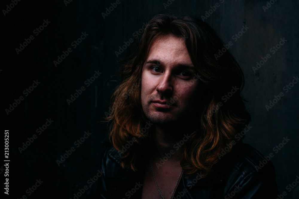 brutal man in a leather jacket on a naked body with long hair. a lonely man is sad and desperate brutal man in a leather jacket on a naked body with long hair. a lonely man is sad and desperate