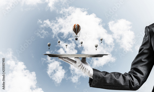 Hand of waitress presenting balloons on tray.