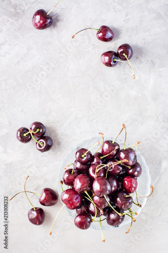 Ripe fresh sweet cherries in a glass bowl on a gray background. Top view