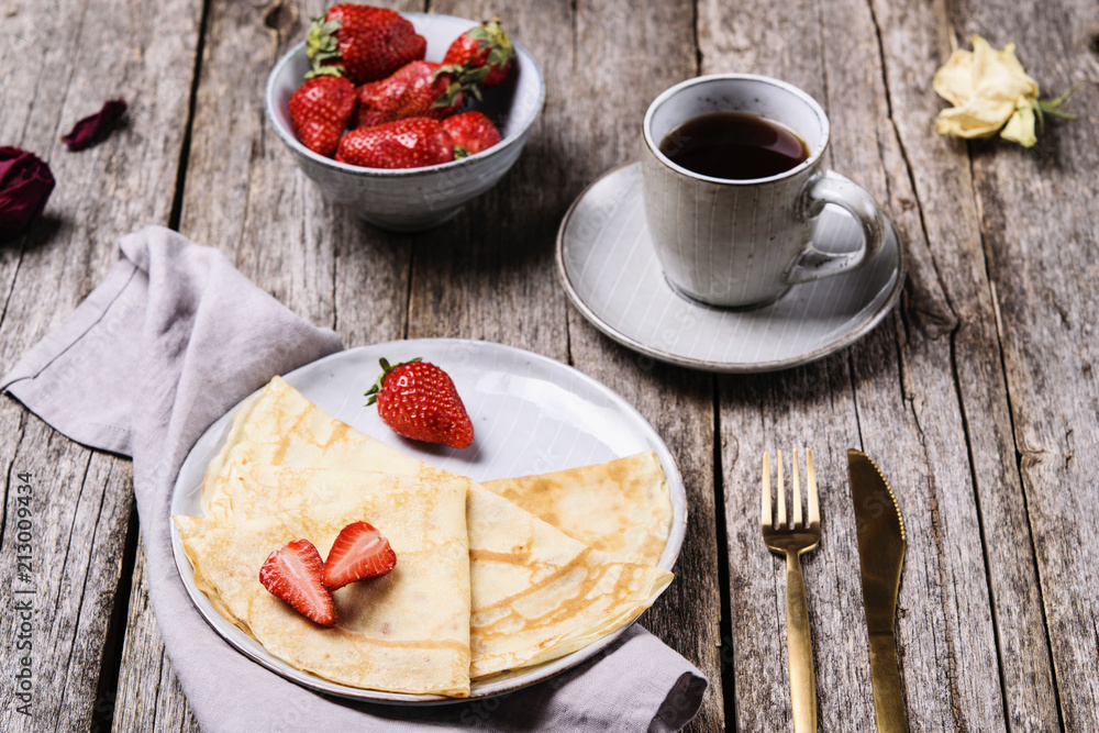 Openwork thin cheese crepes served with strawberry on wooden background. Homemade pancakes. Delicious breakfast Openwork thin cheese crepes served with strawberry on wooden background. Homemade pancakes. Delicious breakfast