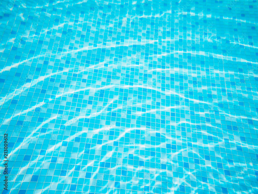 swimming pool top view background, sun reflection on the blue clear water ripples of swimming pool with mosaic bottom.