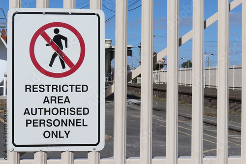 a black, white and red Restricted Area, Authorised Personnel Only warning sign on a fence