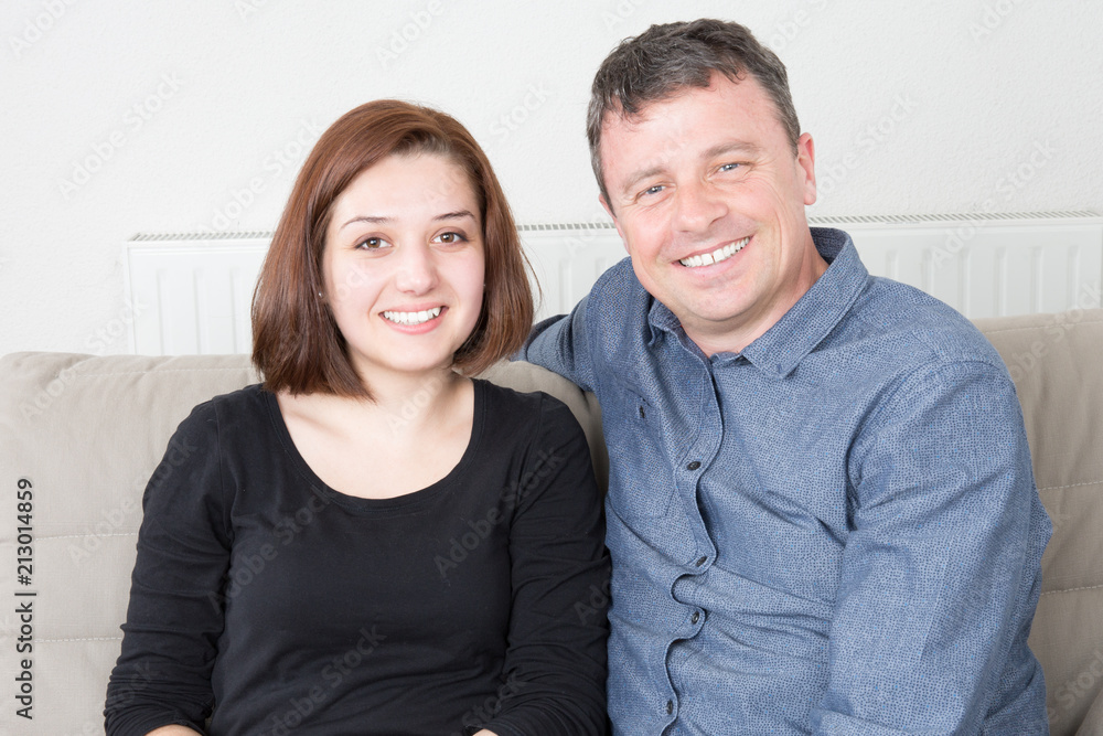 happy smiling young casual couple on home sofa woman on arms of her boyfriend happy smiling young casual couple on home sofa woman on arms of her boyfriend