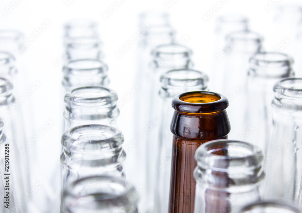 Empty clear glass bottles isolated on white background with one brown in the middle Empty clear glass bottles isolated on white background with one brown in the middle