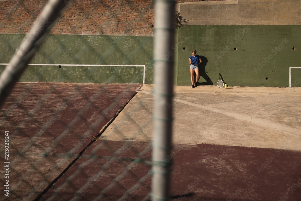 Woman leaning against wall in the tennis court Woman leaning against wall in the tennis court