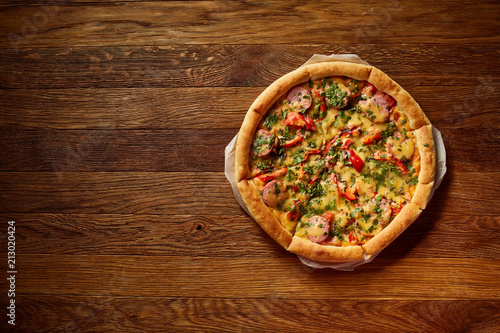 Freshly baked delicious pizza on rustic wooden background, top view, close-up, selective focus.