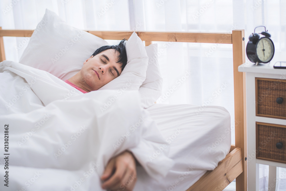 sleepy man on the bed with alarm clock in the morning sleepy man on the bed with alarm clock in the morning