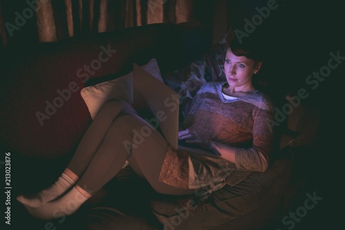 Woman using laptop on sofa in living room photo