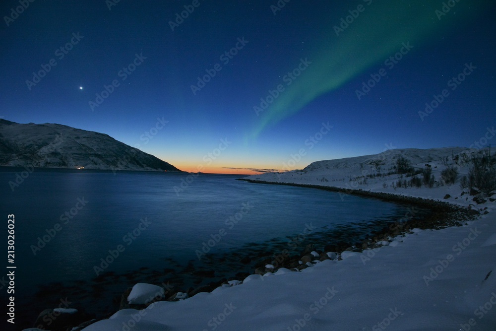 The northern lights (Aurora Borealis) over Seljelvnes, Troms by the sea and the snowy mountains The northern lights (Aurora Borealis) over Seljelvnes, Troms by the sea and the snowy mountains