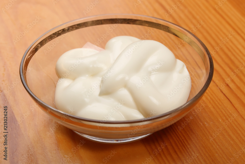 Mayonnaise in a small glass bowl on a wooden table Mayonnaise in a small glass bowl on a wooden table