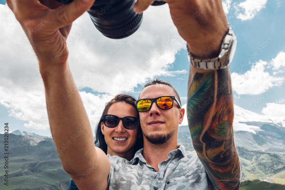 Φωτογραφία A couple of travelers, a guy and a girl, do selfie on a camera against the backd