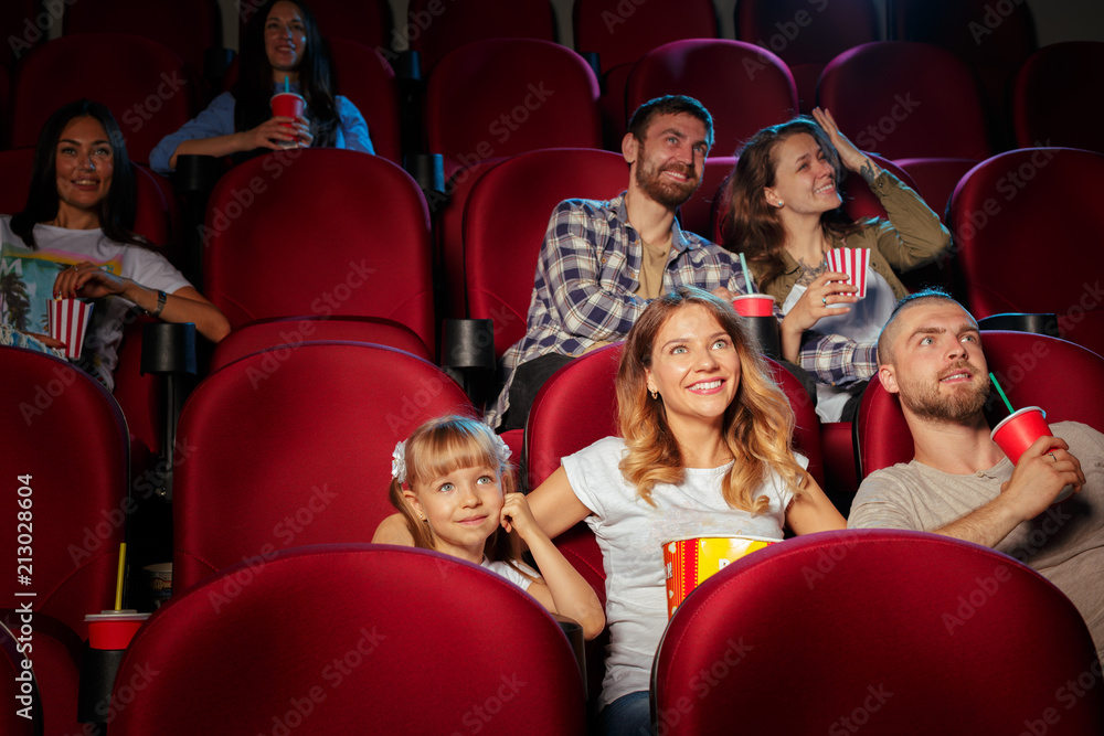 Group of friends sitting in movie theater with popcorn and drinks Group of friends sitting in movie theater with popcorn and drinks