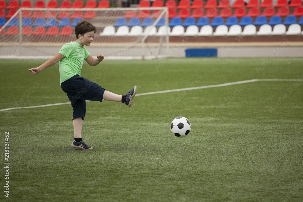 child run soccer (football) player. Boy with ball on green grass