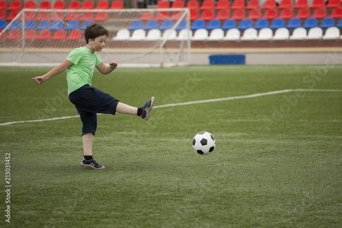child run soccer (football) player. Boy with ball on green grass