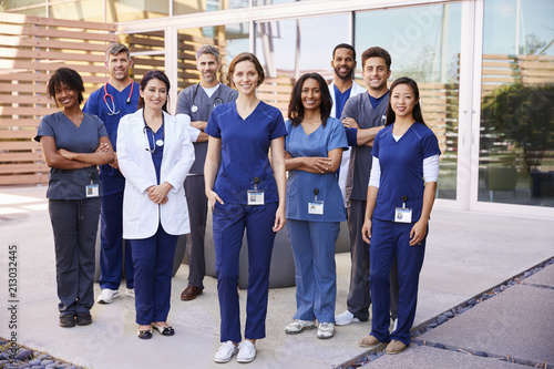 Healthcare team with ID badges stand outdoors, full length photo