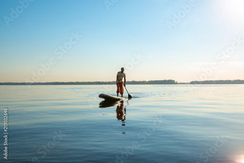 Man is training on a SUP board on a large river © sanechka