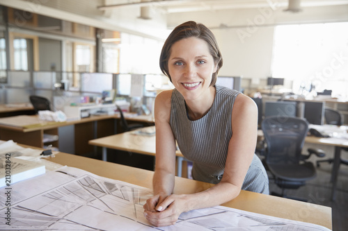 Young female architect leaning on desk smiling to camera photo