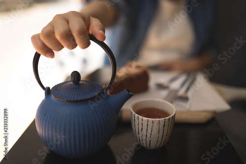 Pregnant woman holding teapot at cafe