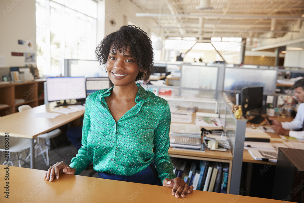 Black female architect in open plan office smiling to camera Black female architect in open plan office smiling to camera