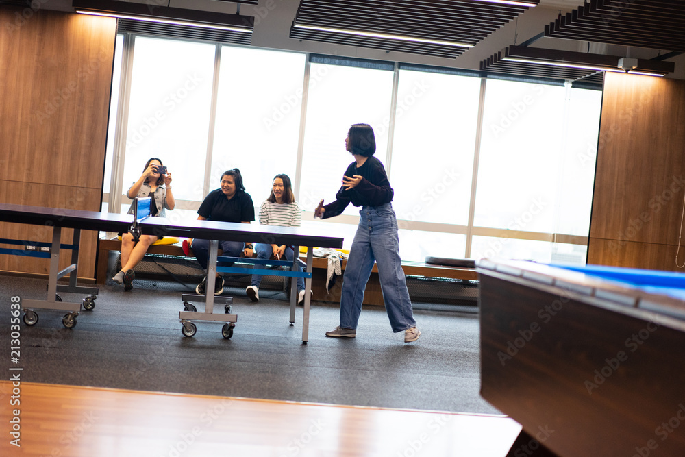 Girls is playing table tennis at the office.