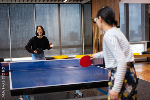 Girls is playing table tennis at the office.