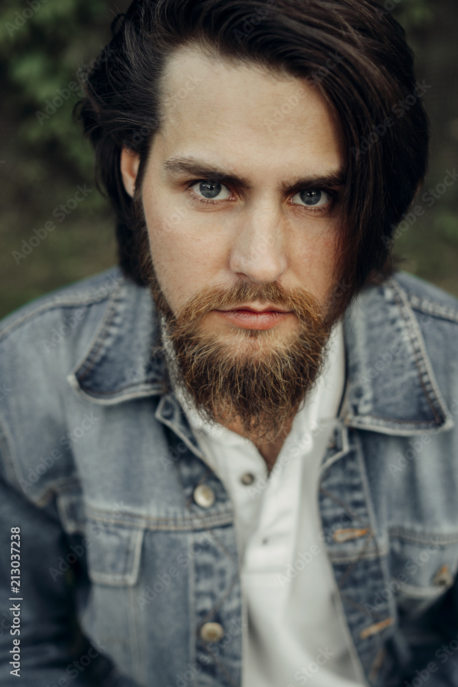 A large-sized portrait of a bearded dark-haired guy in a blue jeans similar to Jared Leto A large-sized portrait of a bearded dark-haired guy in a blue jeans similar to Jared Leto