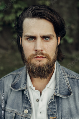 Photos A large-sized portrait of a bearded dark-haired guy in a blue jeans similar to