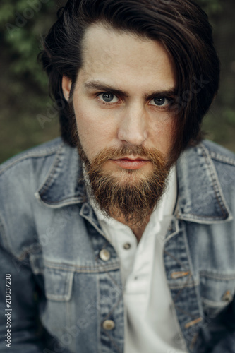 Photos A large-sized portrait of a bearded dark-haired guy in a blue jeans similar to