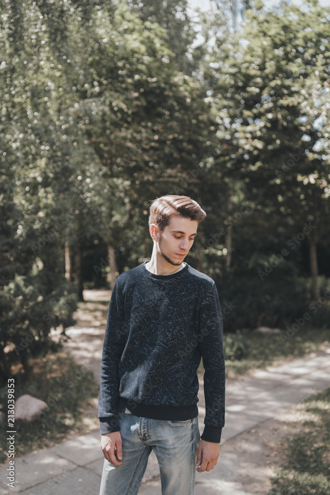 Portrait of a slender dark-haired guy in golf and jeans in urban areas. Portrait of a slender dark-haired guy in golf and jeans in urban areas.