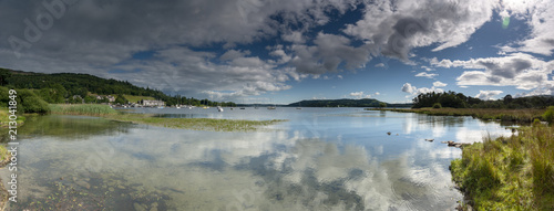 Panoramic view of still waters and late afternoon sunshine on Lake Windermere from Borrans Park, Ambleside, Cumbria, UK