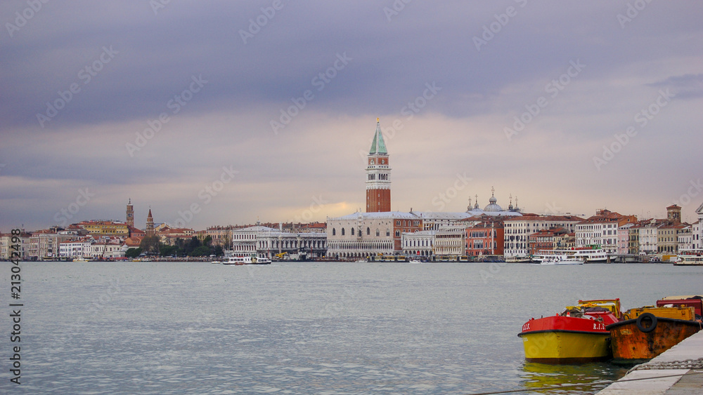 Classic view of St Marks and the Doge Palace across from Giudecca at sunset with spring shower clouds turning the sky violet and purple, Venice, Italy
