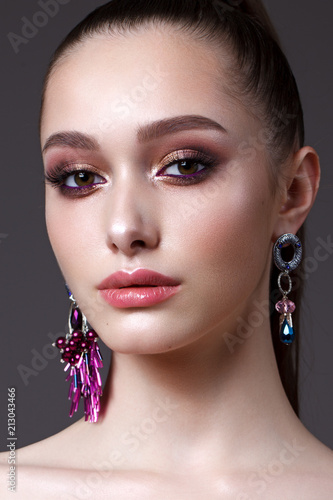 Beautiful young model with professional day makeup, perfect skin, long earrings
