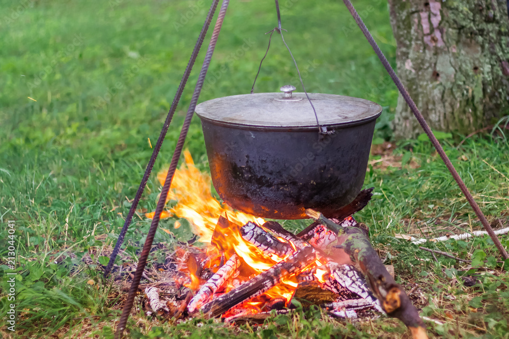 A cauldron on the fireplace while cooking on a journey. Rest and lunch on the nature_ A cauldron on the fireplace while cooking on a journey. Rest and lunch on the nature_
