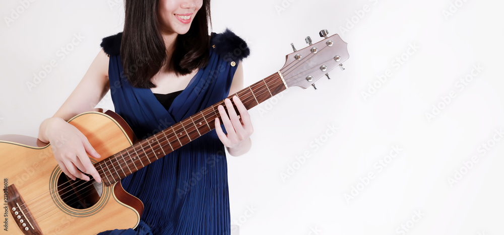 Obraz premium Young teenage woman playing a acoustic guitar isolated over white background - with copy space for ads and banner.