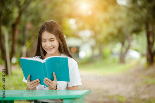 Asian girl reading book at park in summer sunset light. asian woman reading book in Thailand. asian Beautiful woman reading a book at table.