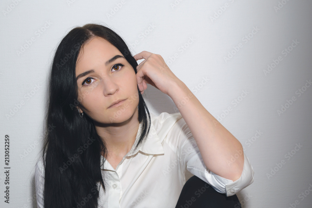 portrait of a girl with black hair, brown eyes, dressed in white shirt and  holding her hand near her head against a white background Stock Photo |  Adobe Stock