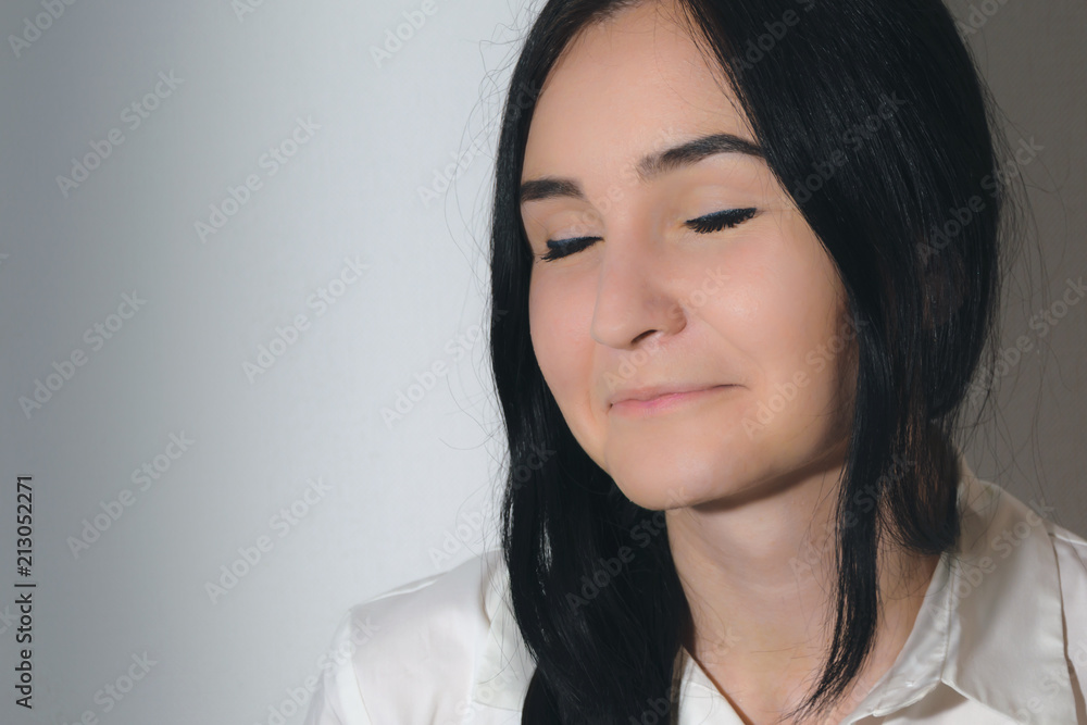 portrait of a girl with black hair and eyes closed, dressed in white shirt on a white background portrait of a girl with black hair and eyes closed, dressed in white shirt on a white background