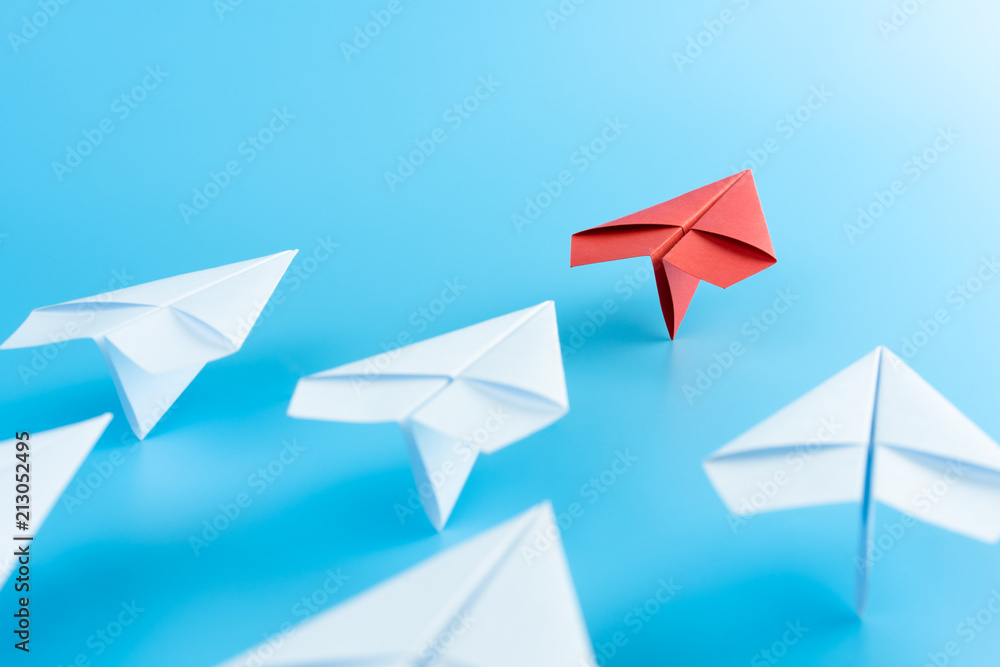 Leadership concept with red paper plane leading among white on blue background Leadership concept with red paper plane leading among white on blue background